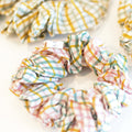 Hand block printed scrunchies in a soft pink with checkered pattern, made from cotton silk fabric.