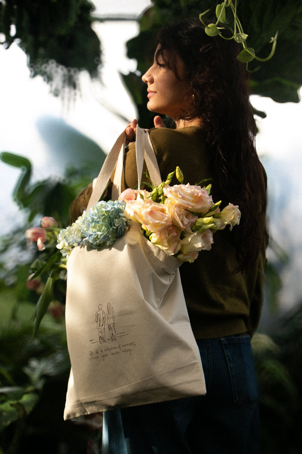 Woman holding a tote bag with flowers against a blurred natural background